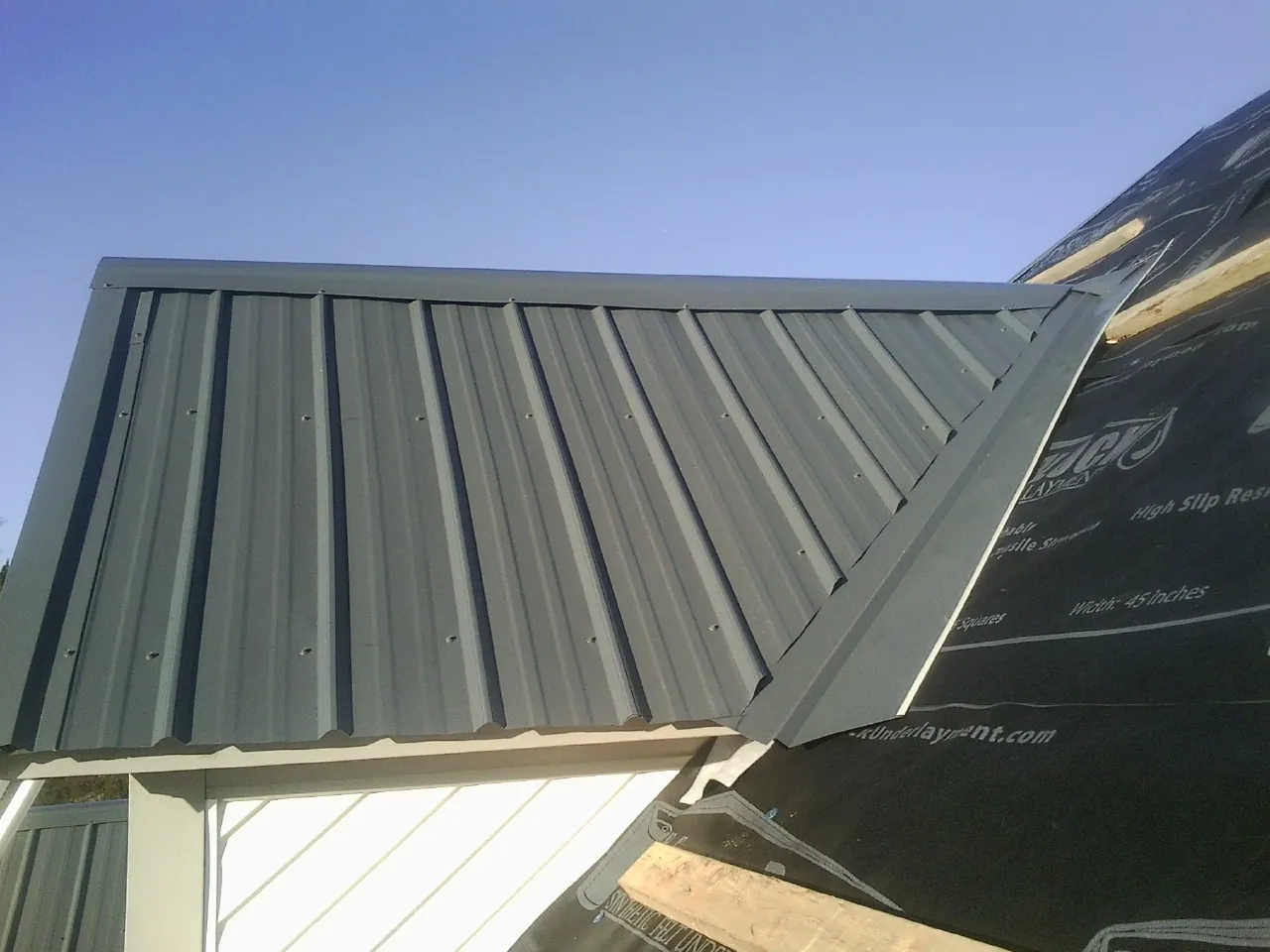 Gray metal roof panels going on over a garage gable in Glendora