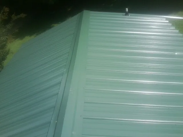 New green metal panels meeting at the ridge of a roof — Flat Roof Repair work by our crew in Glendora