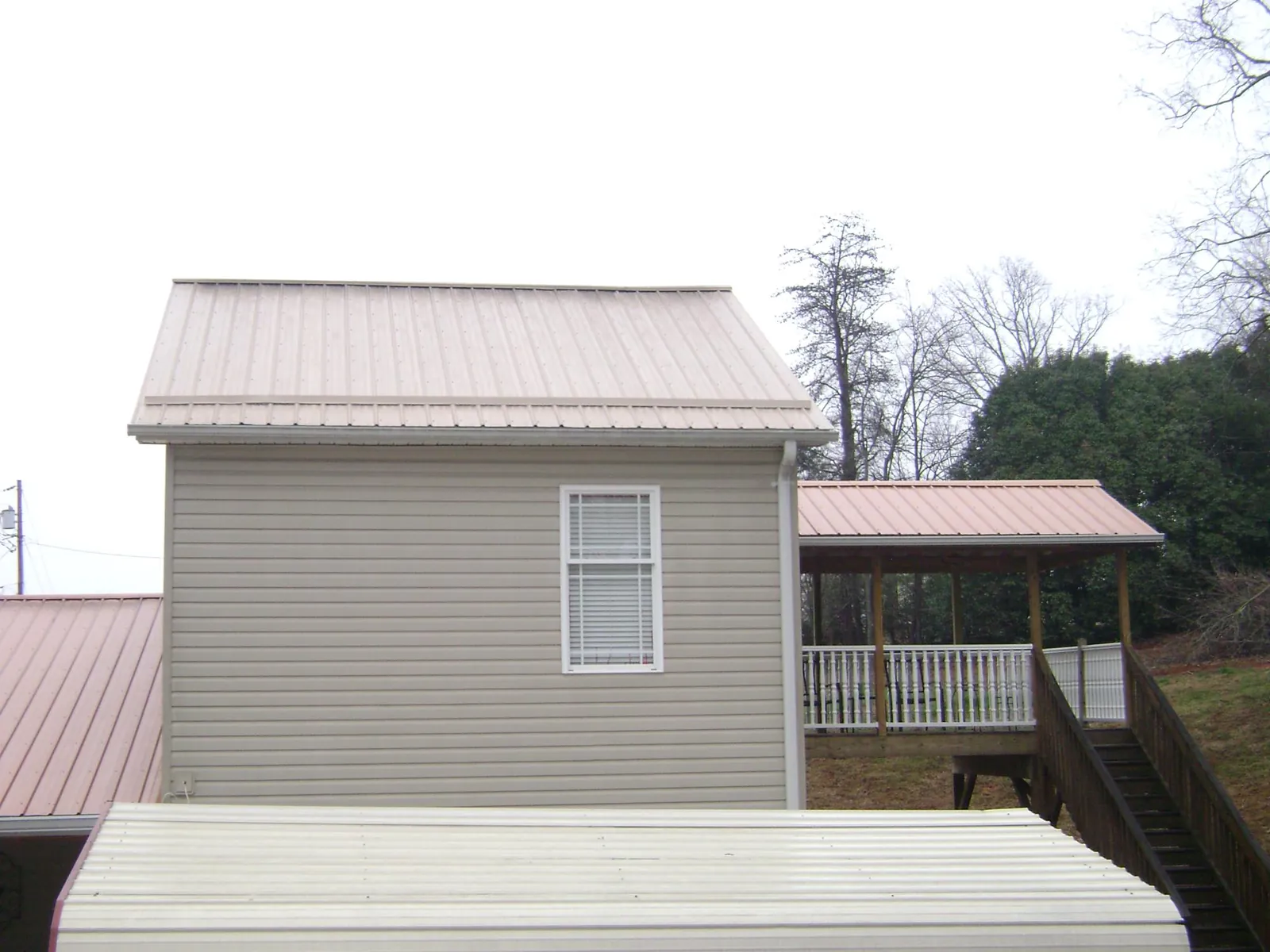 Tan metal roofs on a two story addition and attached porch, from a Roof Replacement job in Glendora