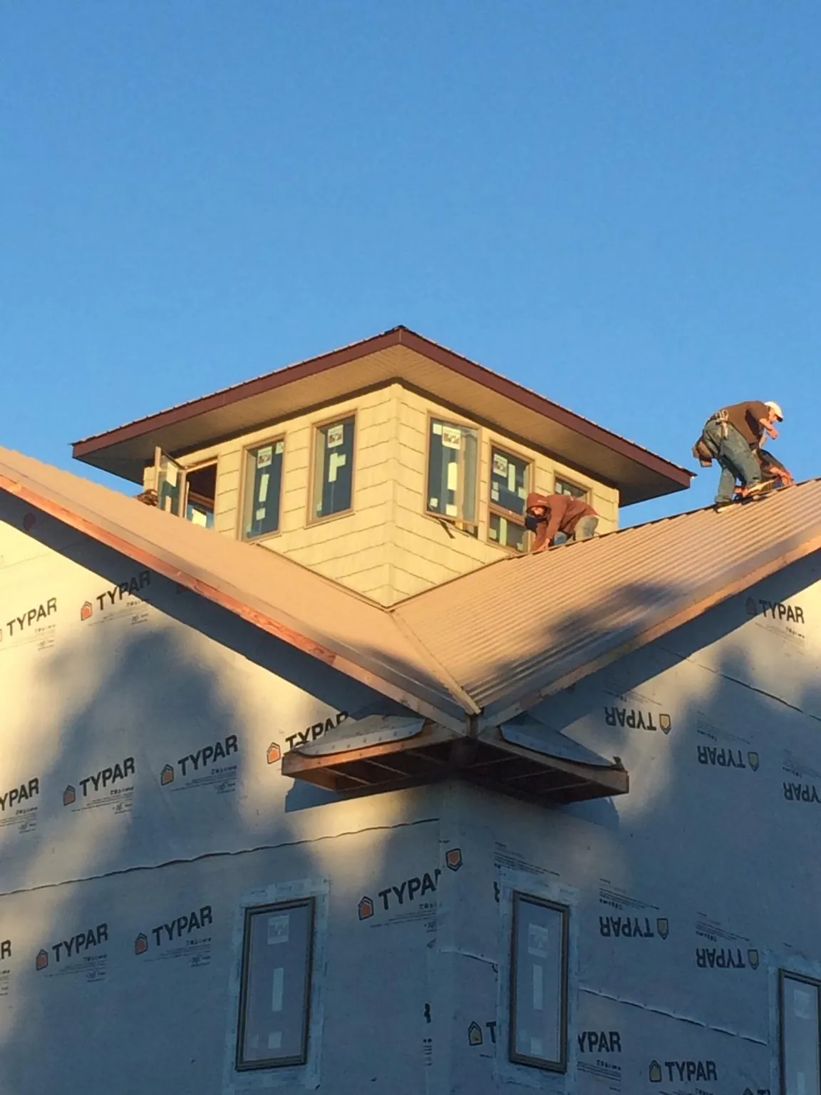 Roofers working around a rooftop cupola on a new metal roof at sunset — Roof Waterproofing in Glendora by Roofing Brothers